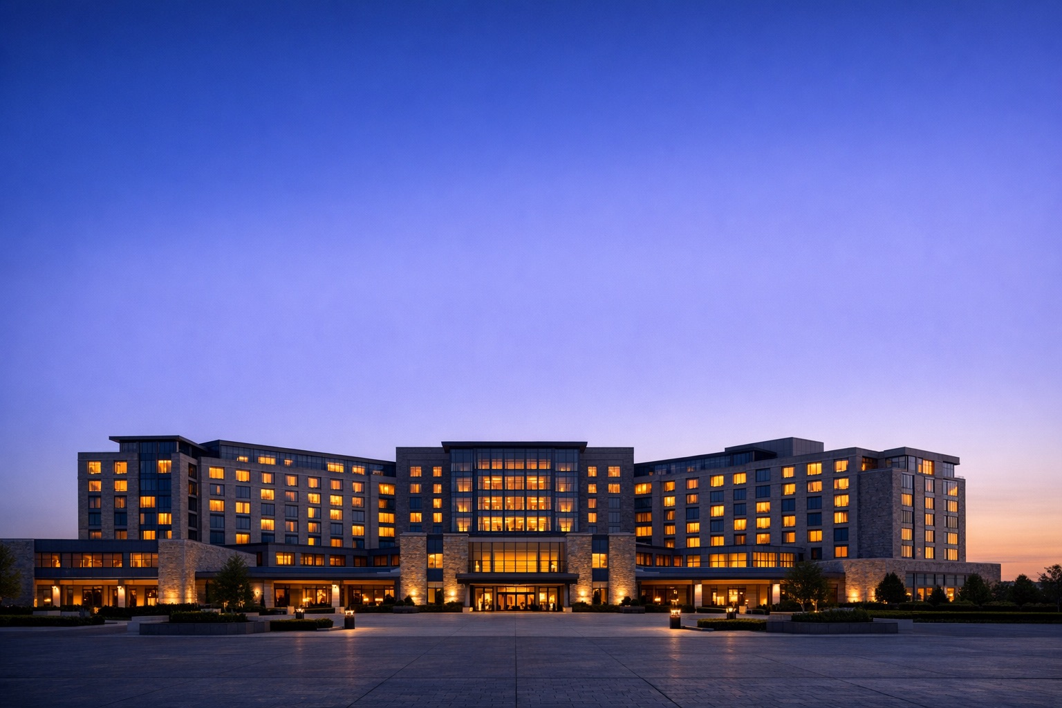 A large hotel exterior at dusk with interior lights on.